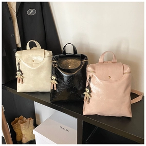 Detail of glossy pleated PU leather texture and cute doll pendant on stylish backpacks