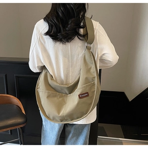 Macro shot of large khaki nylon tote bag showing durable texture and brand logo patch