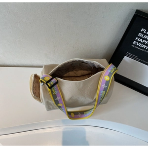 Interior detail of the beige cylindrical crossbody bag showing logo lining and inner pocket