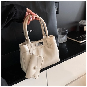 Detail of cream glossy leather bucket bag featuring a metal twist lock and coin purse