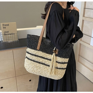 Detail of woven tote bag featuring black and beige stripes with brown leather handle