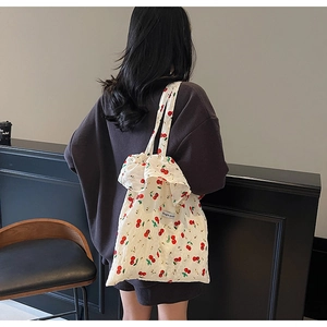 Detail of canvas tote bag with red cherry print and Magic pocket tag on white fabric