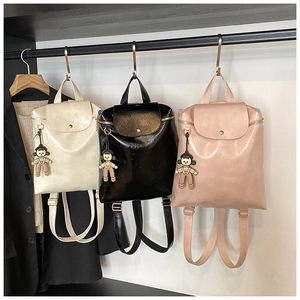 Three glossy PU leather mini backpacks in white, black and pink with cute doll pendants