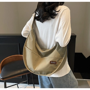 Side view of large khaki nylon hobo bag featuring external pockets and brown logo patch