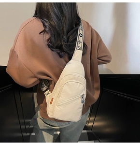Close-up of beige nylon chest bag featuring jacquard strap and orange side label detail