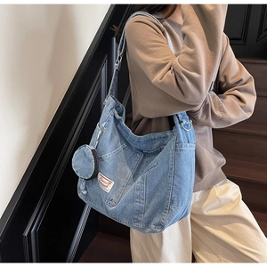 Dettaglio della borsa tote in denim blu con tasca frontale e borsellino rotondo rimovibile