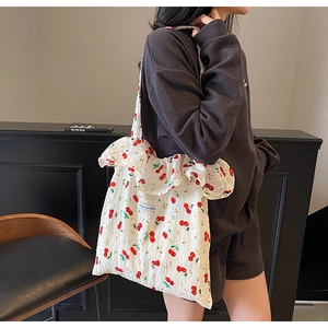 Detail of cherry print tote bag with ruffled edges and Magic Pocket label on fabric