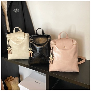 Detailed view of three mini backpacks in cream, black, and pink with plush pendants
