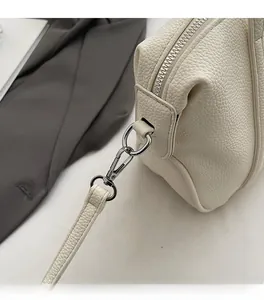 Close-up of off-white lychee grain leather handbag with silver metal zippers and hooks