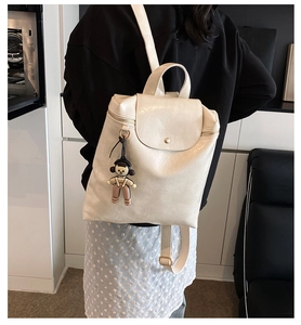 Detail of cream-colored backpack in wrinkled PU leather with cartoon pendant