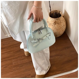 Detail of light blue shell handbag with decorative belt buckle and dual handles