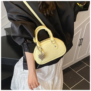 Gros plan d'un mini sac oreiller jaune en cuir avec pendentif cœur sur le mannequin
