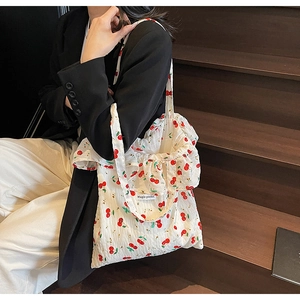 Close-up of white tote bag with red cherry floral print and Magic pocket woven label