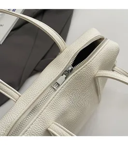 Detailed macro shot of silver metal zipper and white lychee grain leather on handbag