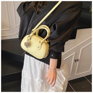 Sac polochon jaune clair en cuir grainé avec breloque cœur porté en bandoulière
