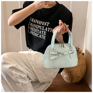 Close-up of mint blue shell bag featuring decorative belt buckle and metal zipper detail