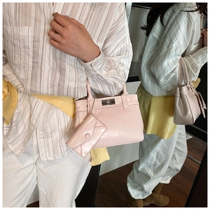 Detail view of pink glossy bucket bag with twist lock and mini charm via mirror reflection