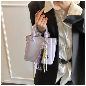 Detail of light purple bucket bag featuring a knotted handle and colorful braided charm