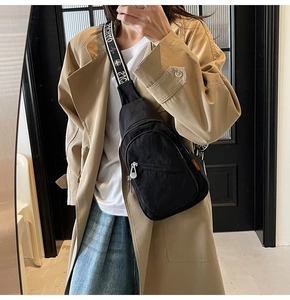 Model showcasing a black nylon crossbody chest bag with a wide printed shoulder strap
