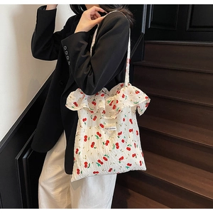 Close-up of white tote bag with cherry print, ruffle edges and Magic pocket label