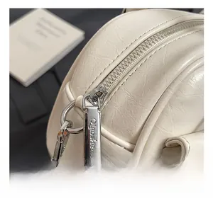 Detailed close-up of premium silver zipper and engraved hardware on white leather bag