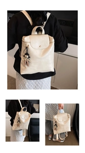 Detail of off-white faux leather backpack with lychee texture and cute doll pendant
