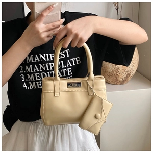 Detail of beige bucket bag featuring a silver twist lock and matching envelope charm