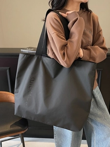 Minimalist large black tote bag with SUIBAG lettering on a stylish female model