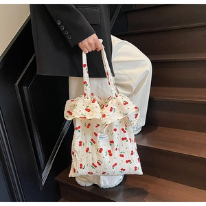 Detail of white canvas tote with red cherry print, ruffle edges and Magic pocket tag