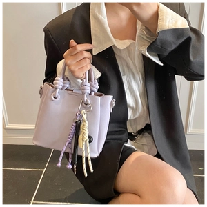 Detail of lavender bucket bag with knot handle and colorful woven rope charm in model shot