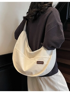 Minimalist beige nylon tote bag with crescent shape and large front pocket on model
