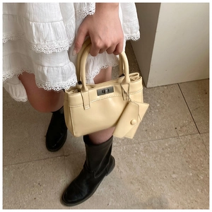Detail of creamy yellow bucket bag with metal turn-lock closure and small matching pouch