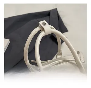 Close-up of white Boston bag with lychee texture leather and snap handle closure