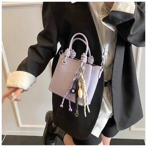 Detail of light purple bucket bag with unique billiard and bowling charms on model