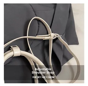 Detail of adjustable off-white faux leather shoulder strap with silver metal buckle