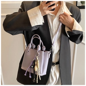 Detail view of lavender bucket bag showing knotted handles and creative decorative pendants