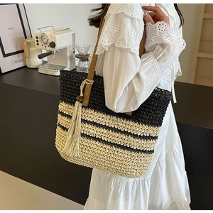 Detail of striped woven tote bag with brown leather strap and beige tassel accent