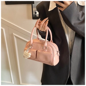 Detailansicht der rosa Boston-Tasche mit Perlenherz-Anhänger und schwarzem Blazer