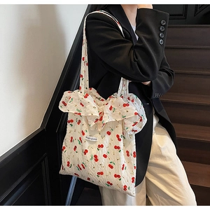Detail of ruffle edges and cherry print on white cotton canvas tote bag with shoulder straps