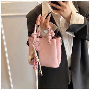 Detail of pink bucket bag with knotted handles and diverse multi-element decorative charms