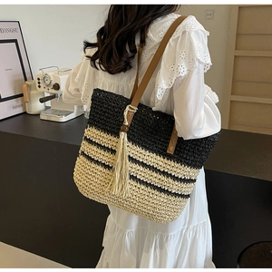 Detail of hand-woven tote bag with beige tassels and striped texture on the side