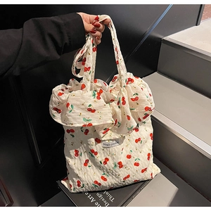 Detail view of white cherry print tote bag with ruffled edges and Magic Pocket label