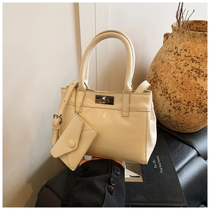 Detail of cream white leather bucket bag with silver twist lock and mini envelope charm