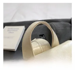 Detail shot of soft beige leather handles with neat stitching and smooth texture