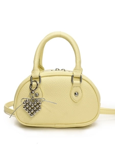 Sac polochon en cuir jaune pâle avec breloque cœur argentée et bandoulière sur fond blanc