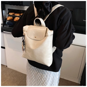 Creamy white leather backpack with flap closure shown in a cozy kitchen lifestyle setting