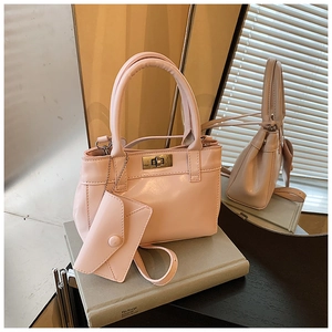 Detail of pink glossy bucket bag with golden twist lock and matching envelope charm