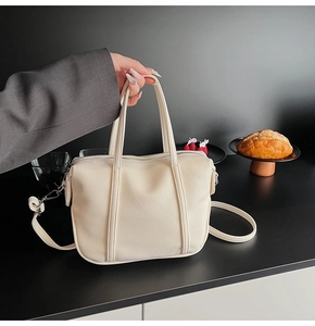 Detail of cream lychee texture handbag with reinforced handles and metal zipper