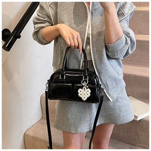 Detail der schwarzen Lackleder Boston Bag mit Perlenherz-Anhänger und Klappentaschen