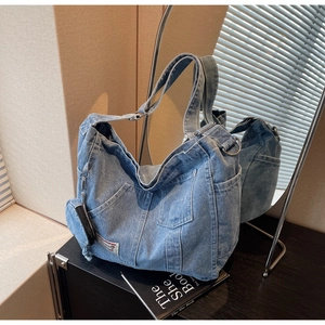 Macro detail of washed denim tote bag showing functional front pocket and small round coin purse